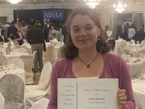 image of student holding up award at a banquet