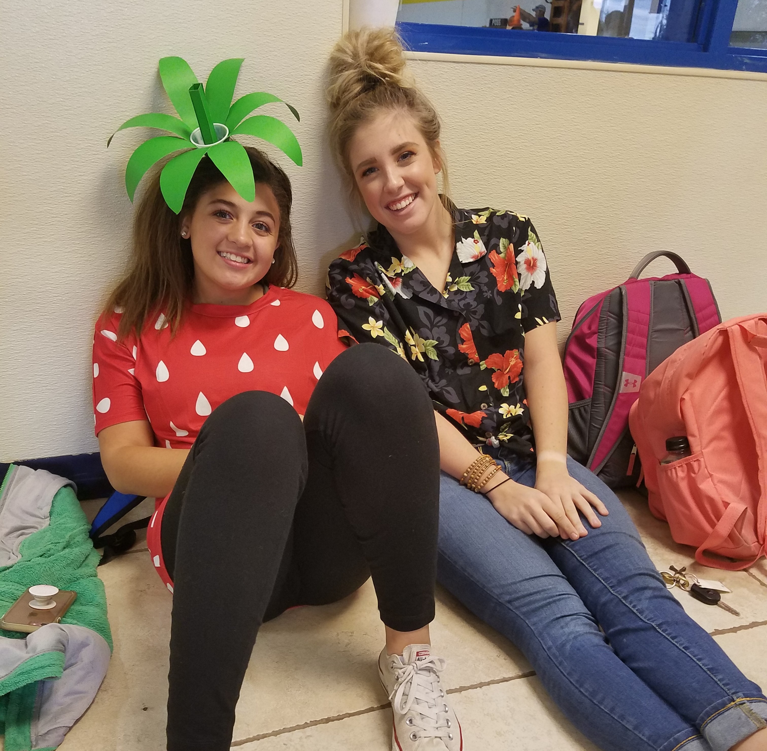 Two girls smiling at the picture, one of them dressed up as a strawberry.