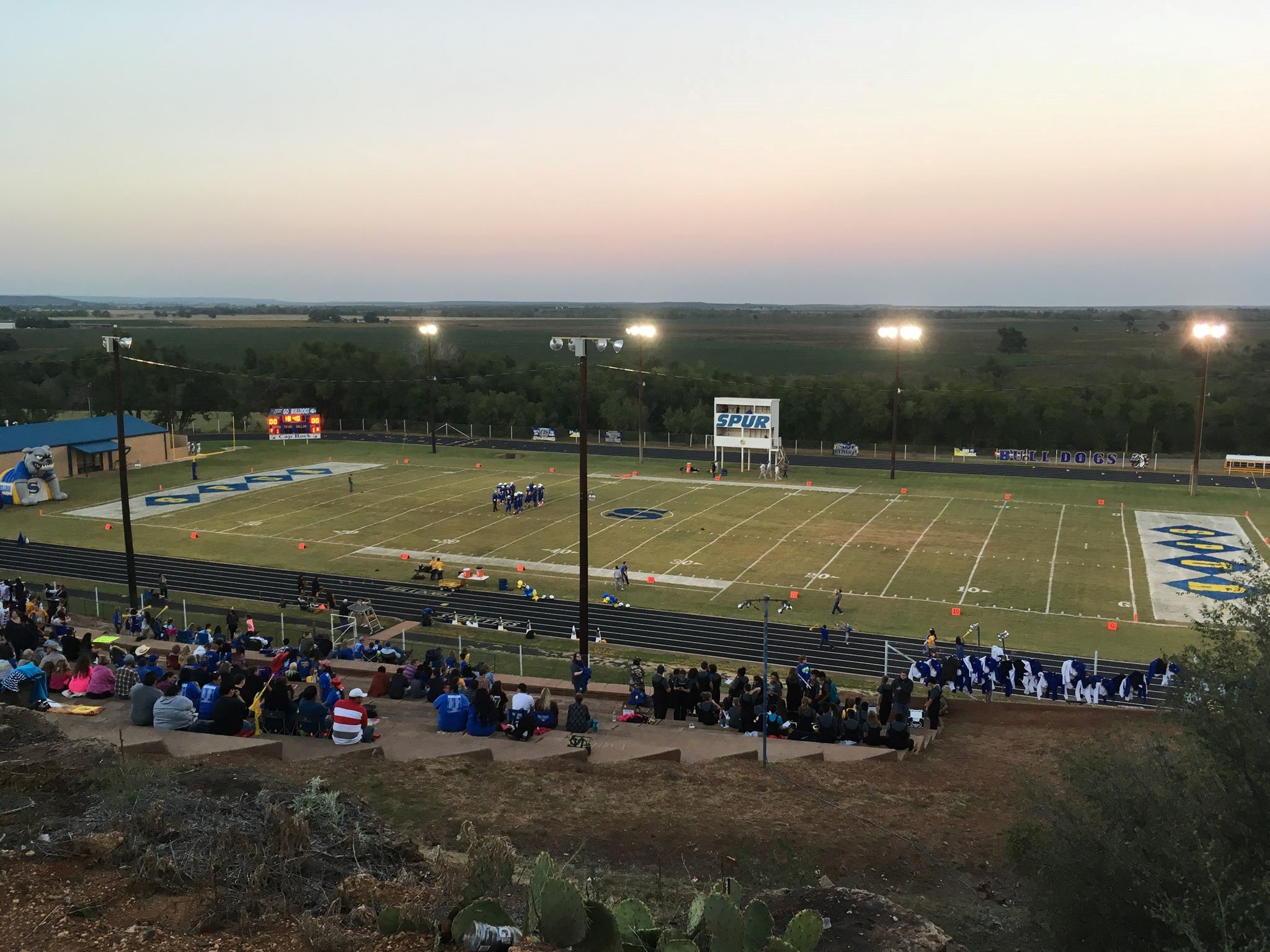 A photo of the football field, a few people gathered around it.