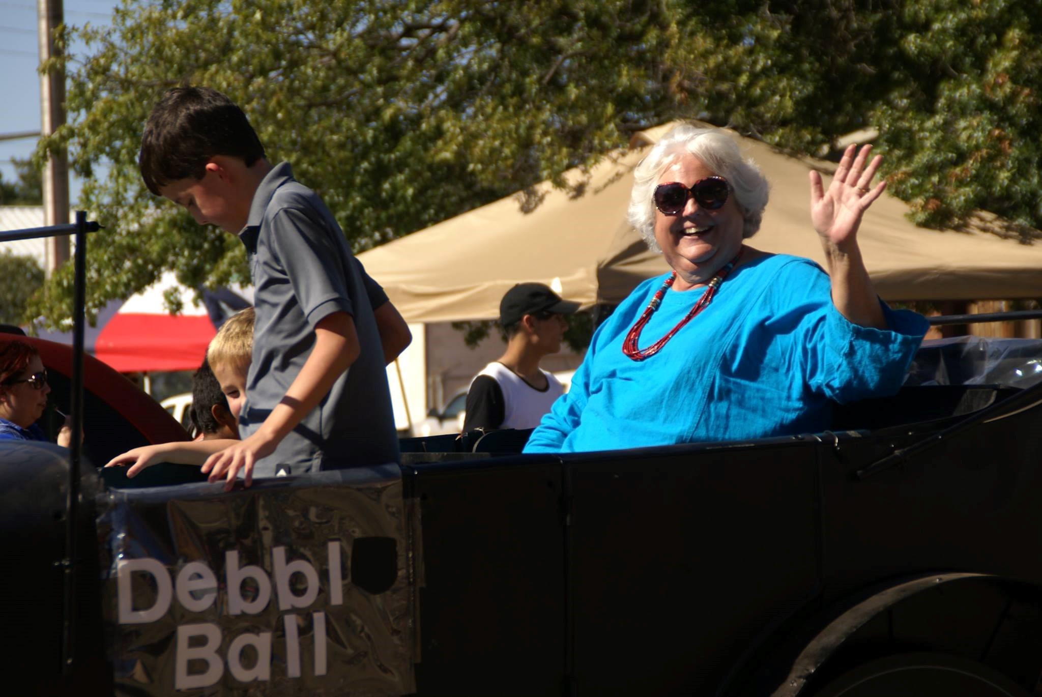A photo of Debbie Ball, waving and cheering from her car.