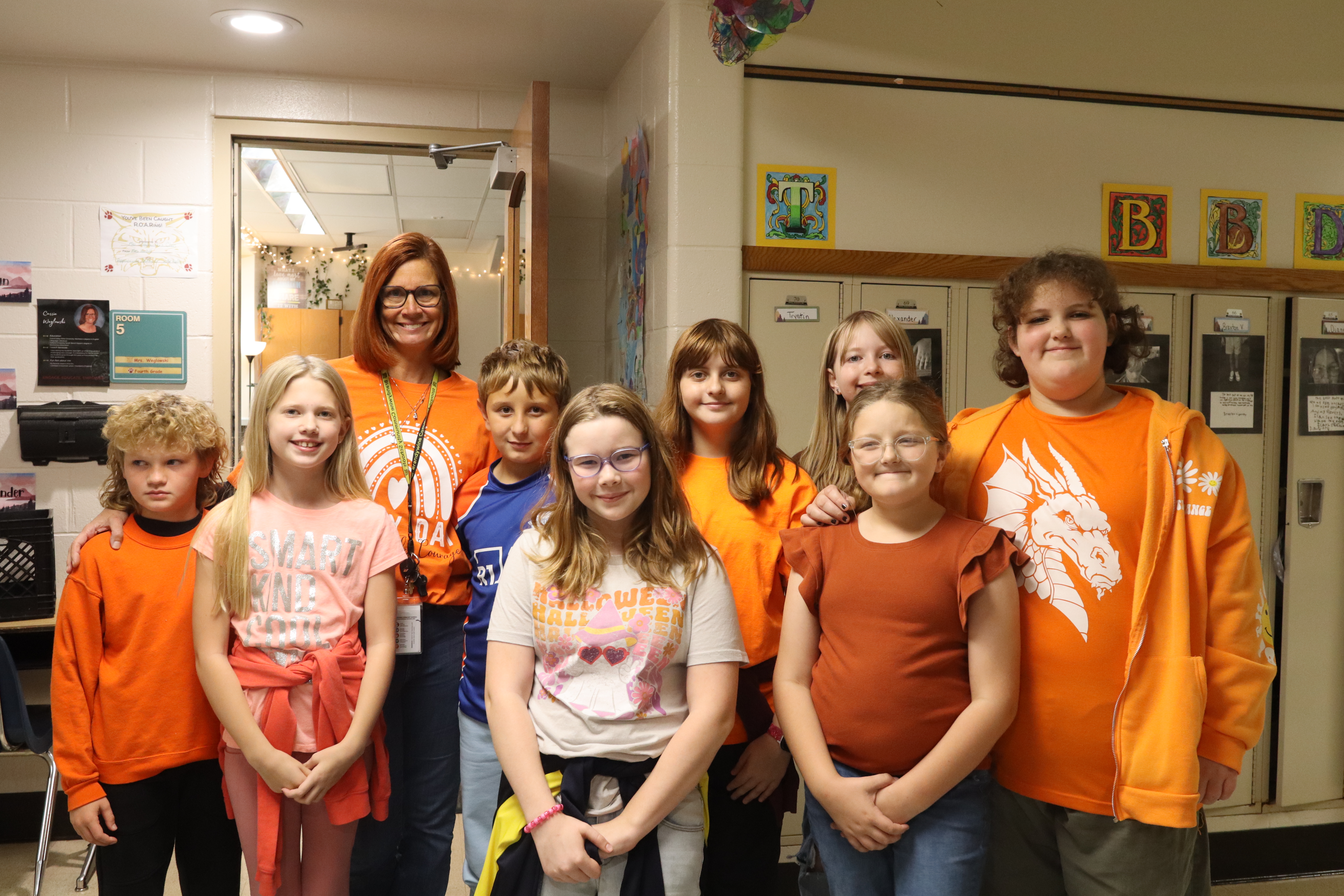 group of kids with teacher wearing orange