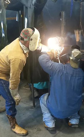 student and teacher welding together in shop 