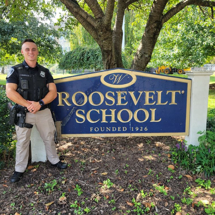 Photo of RIS SRO in front of school sign