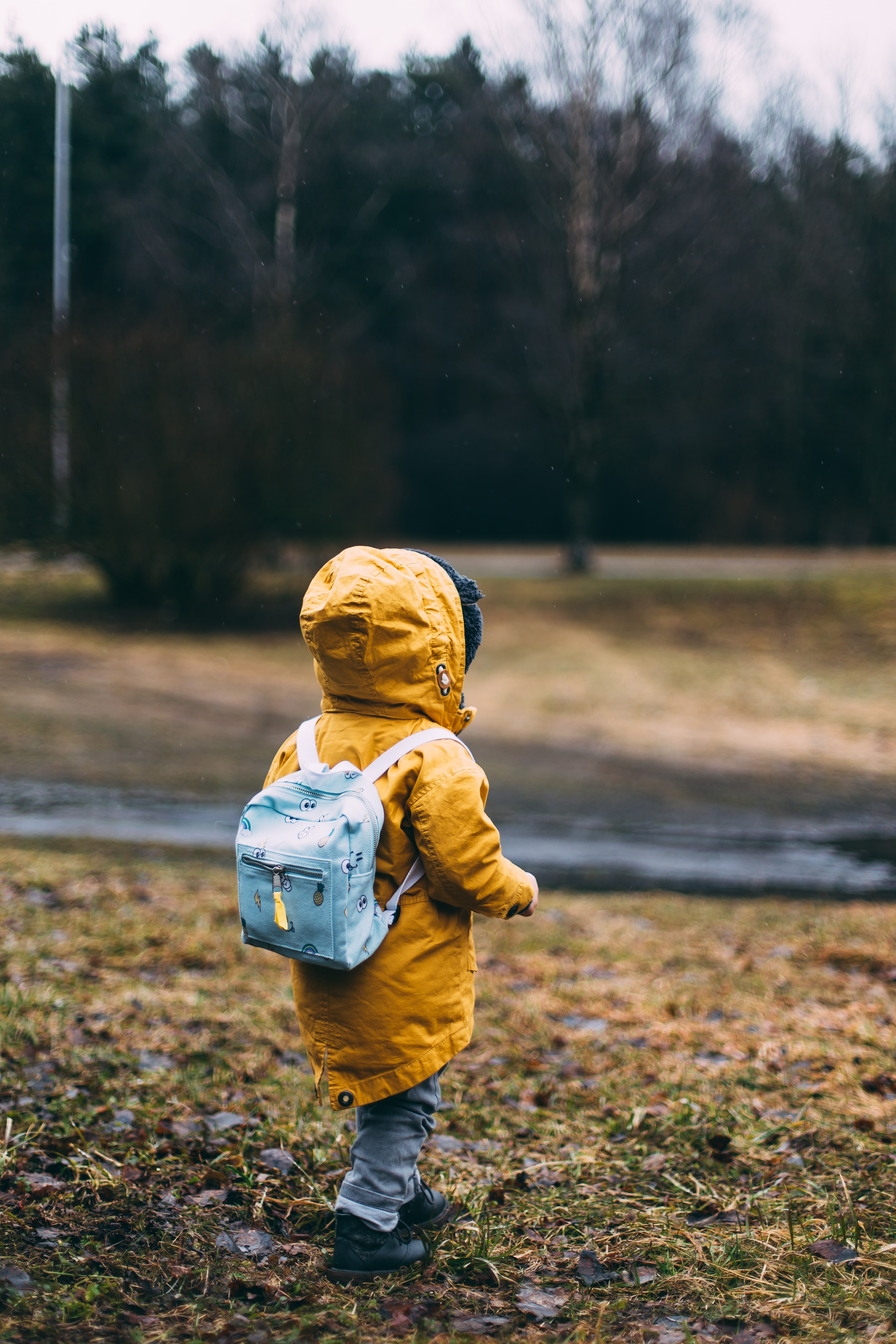 Student walking in the rain with raincoat and backpack