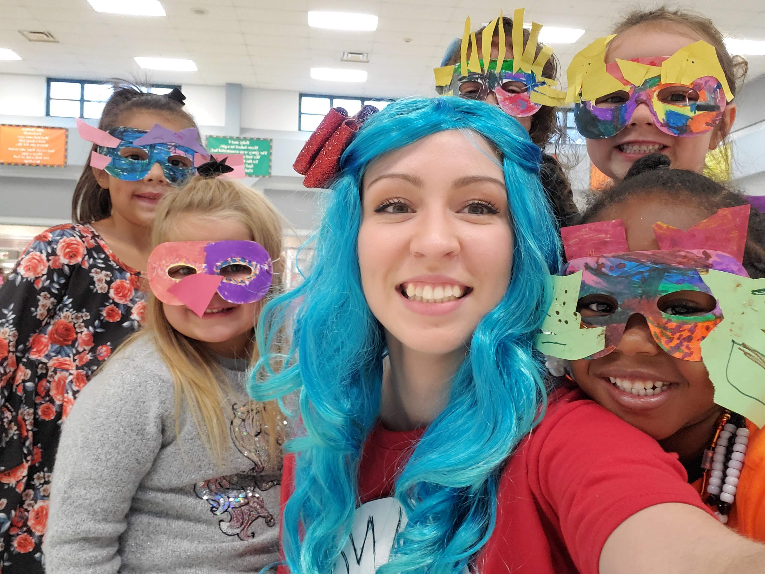 Four students dressed up in masks and a teacher wearing a blue wig