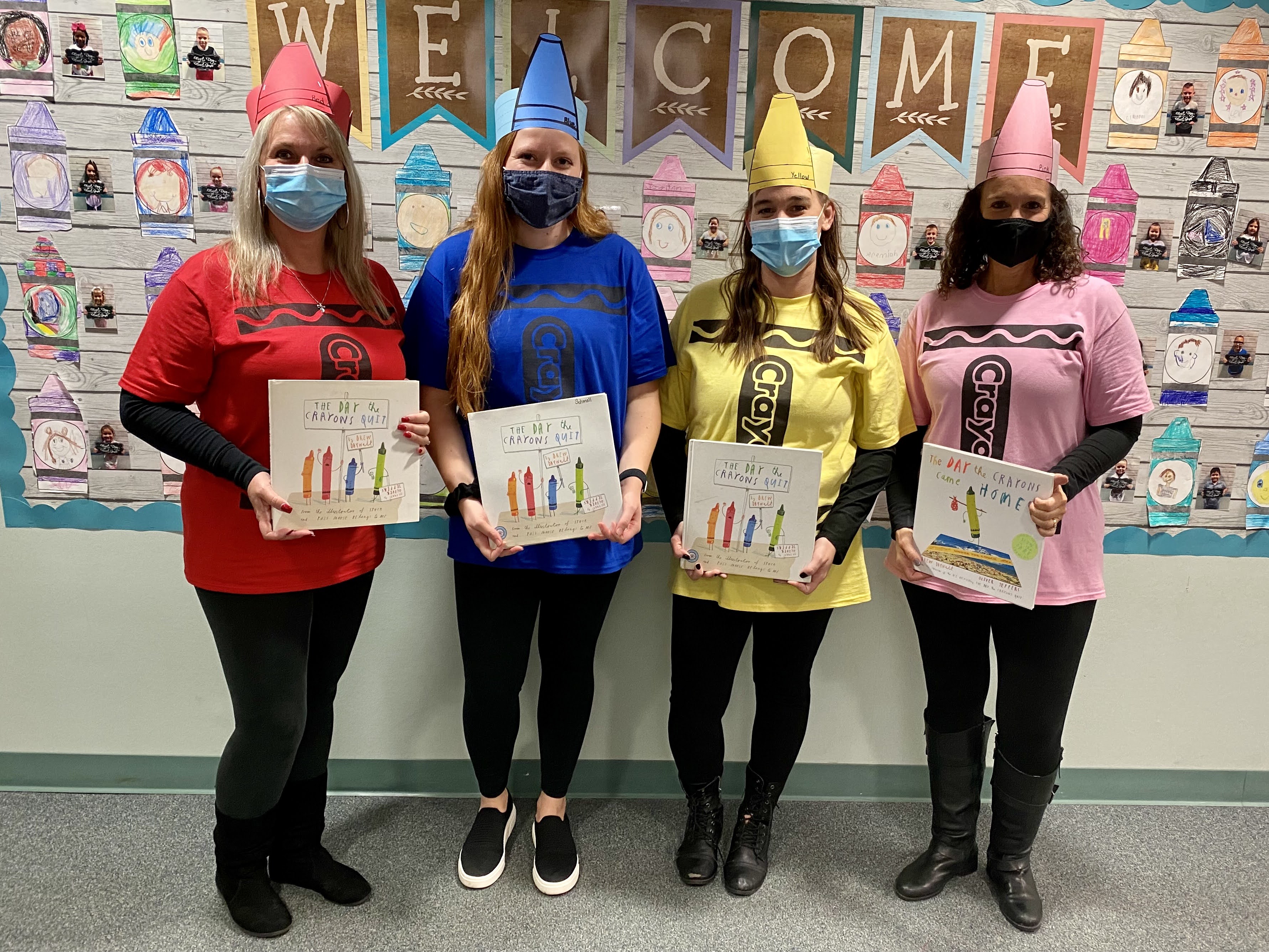 Four teachers holding signs dressed as crayons