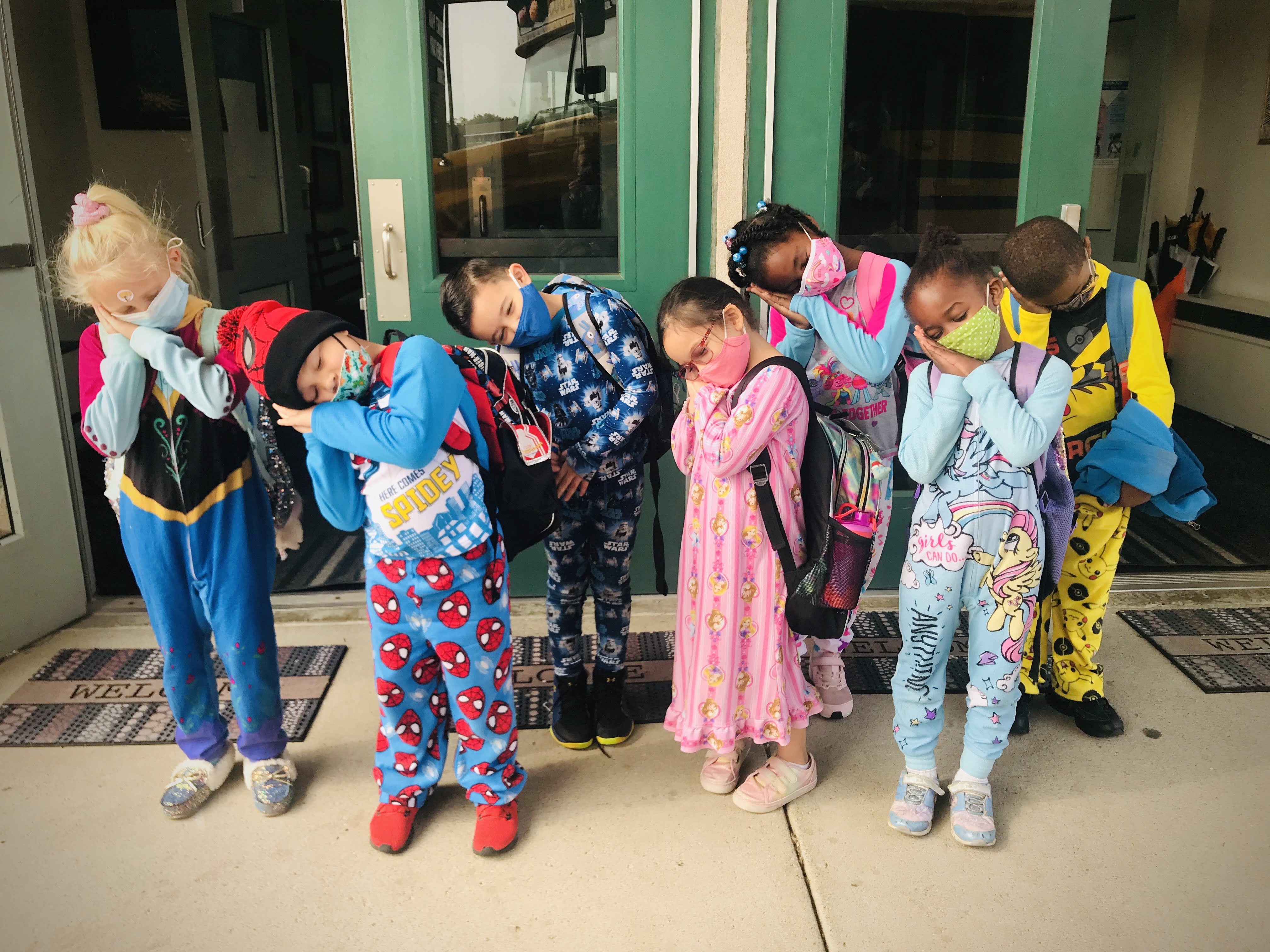 six students dressed in PJs pretending to sleep
