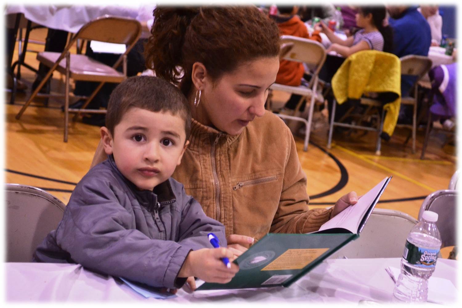 small kid and other sitting on table reading book