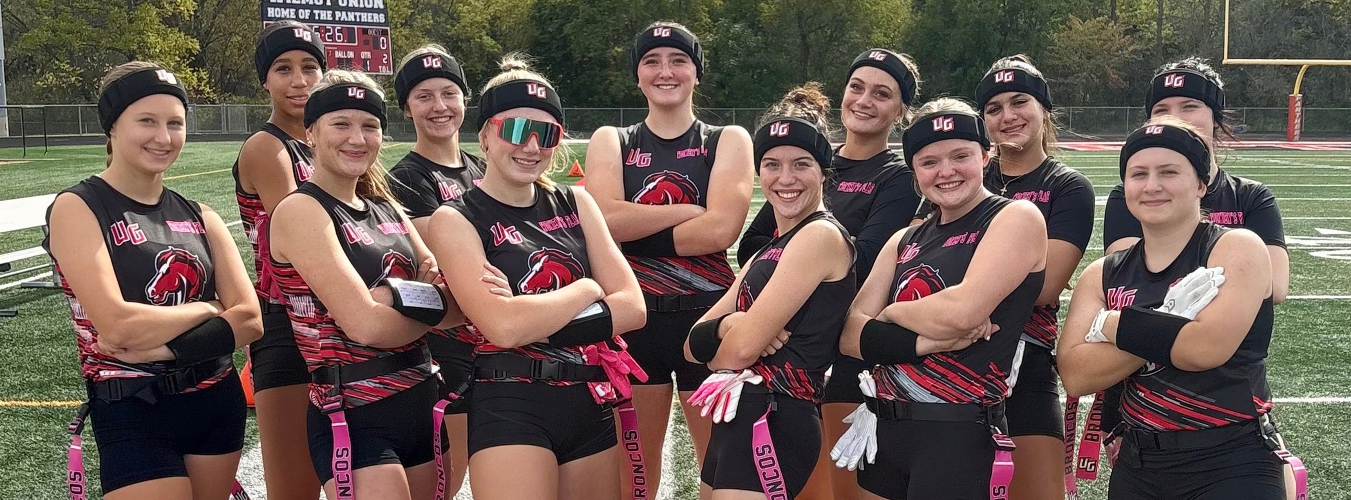 Girls flag football team posing with arms crossed.