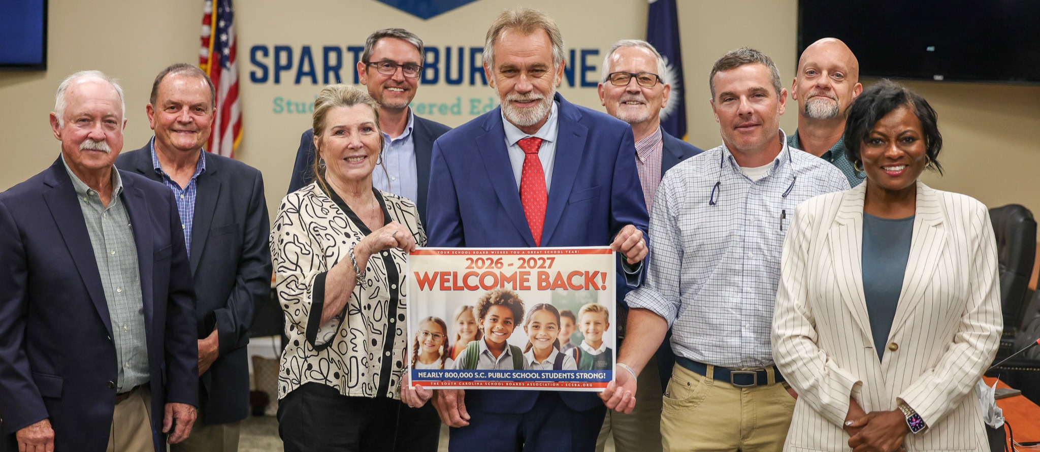 Board of Trustees holding a back to school sign