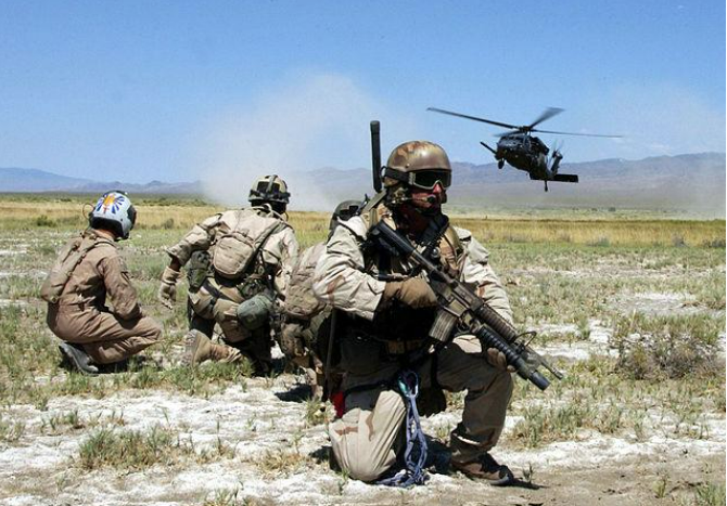 Pararescuemen and a simulated "survivor" watch as a Sikorski HH-60G Hawk helicopter comes in for a landing.