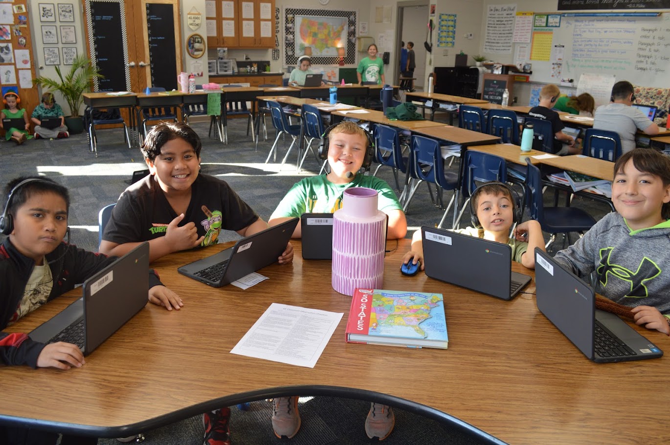 Students smiling at the camera during a break from work on Chromebooks.