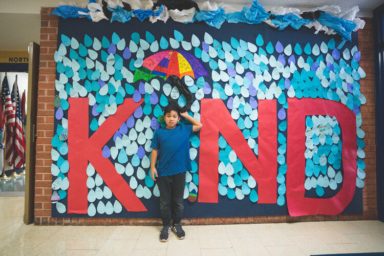 students in front of kind sign