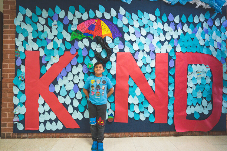students in front of kind sign