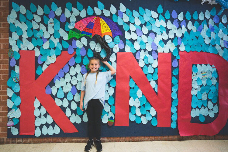 students in front of kind sign