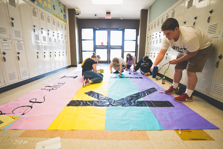 students creating and posing with kind sign