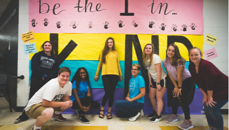 group of students in front of kind sign