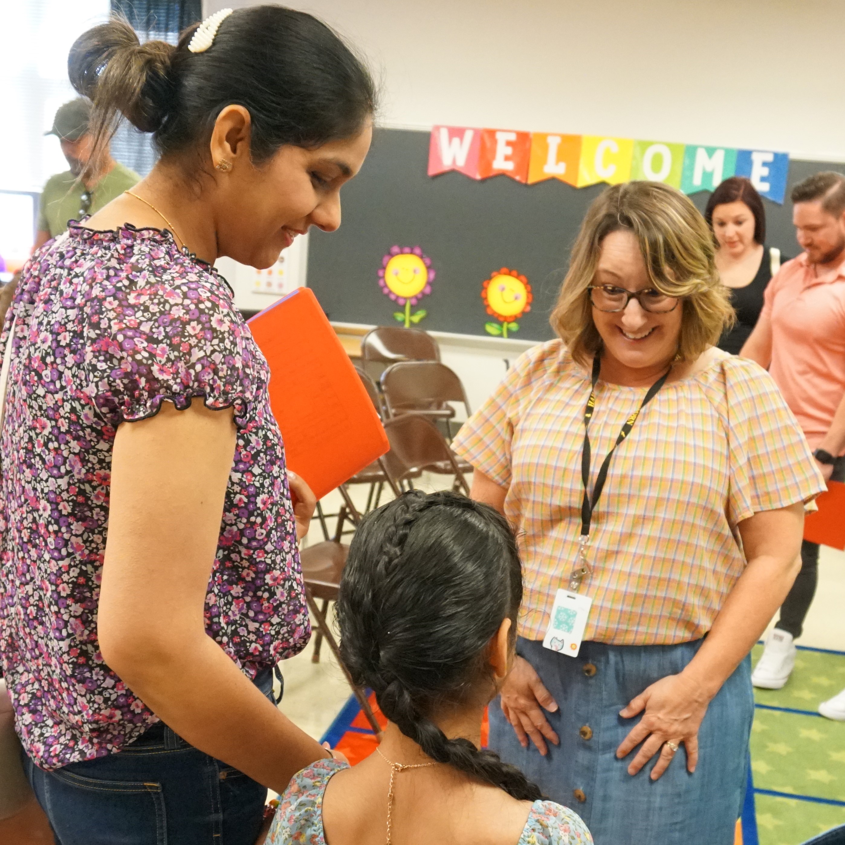 Teacher greets student and family at kindergarten orientation in August