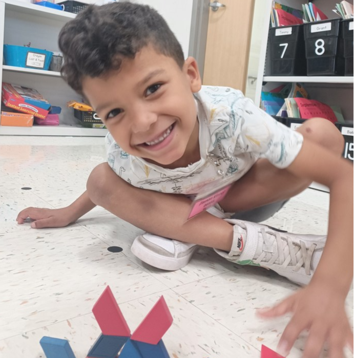 Kindergartener on the floor with blocks solving math problem