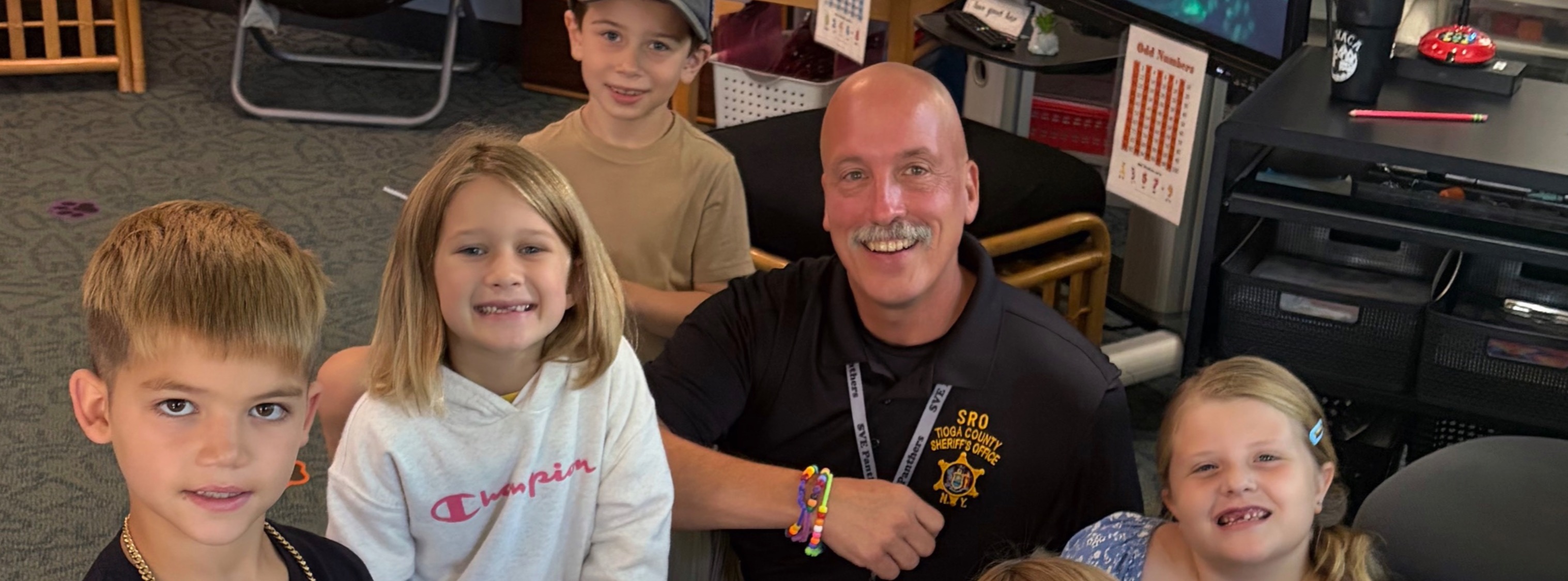 Office Roy makes friendship bracelets with second grade students