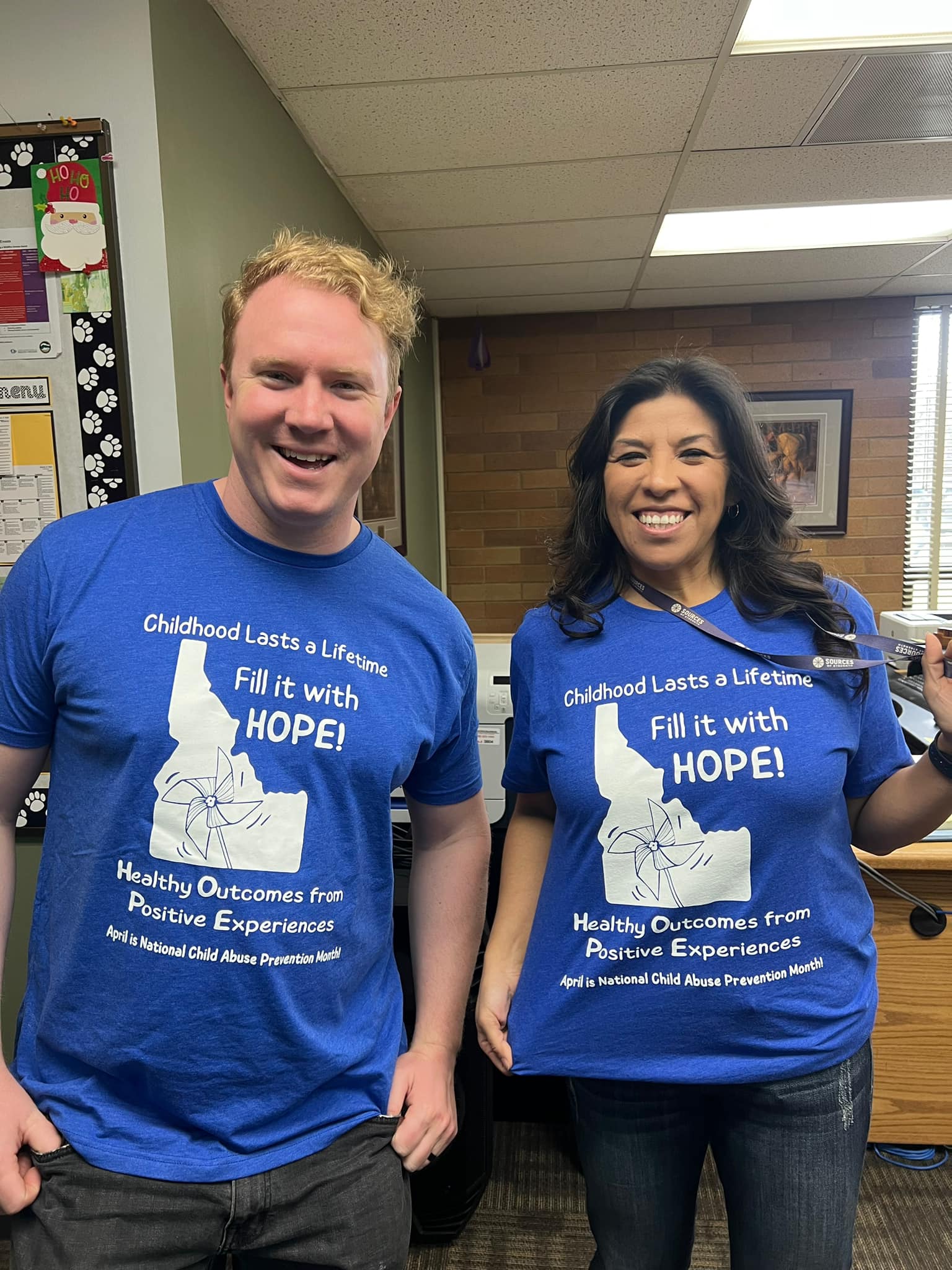 picture of Tom and Liza in the office wearing a blue shirt with a message of hope