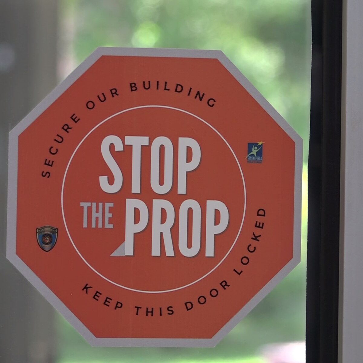 Stop sign that states: STOP THE PROP, Secure Our Building Keep this Door Locked
