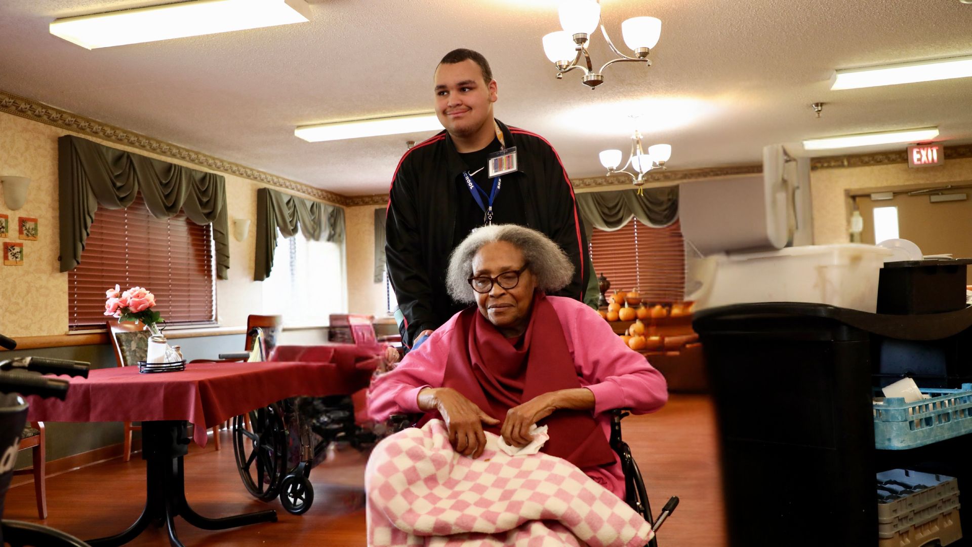 A student pushes a resident in her wheelchair at Villa Springfield