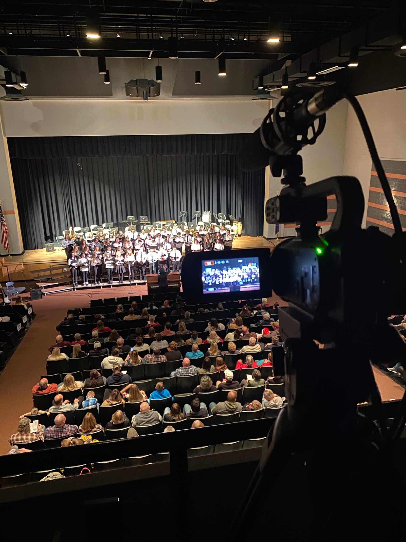Video camera recording student choral concert.