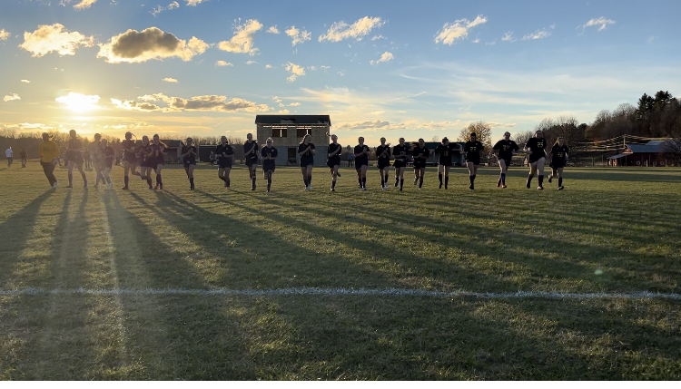 Our girls varsity soccer team making a run after their game. Our girls varsity soccer team is lined up in jersey number order running across the soccer field. 