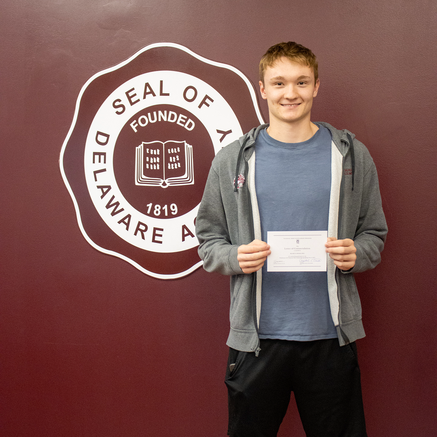 Seamus DeMauro in front of school seal