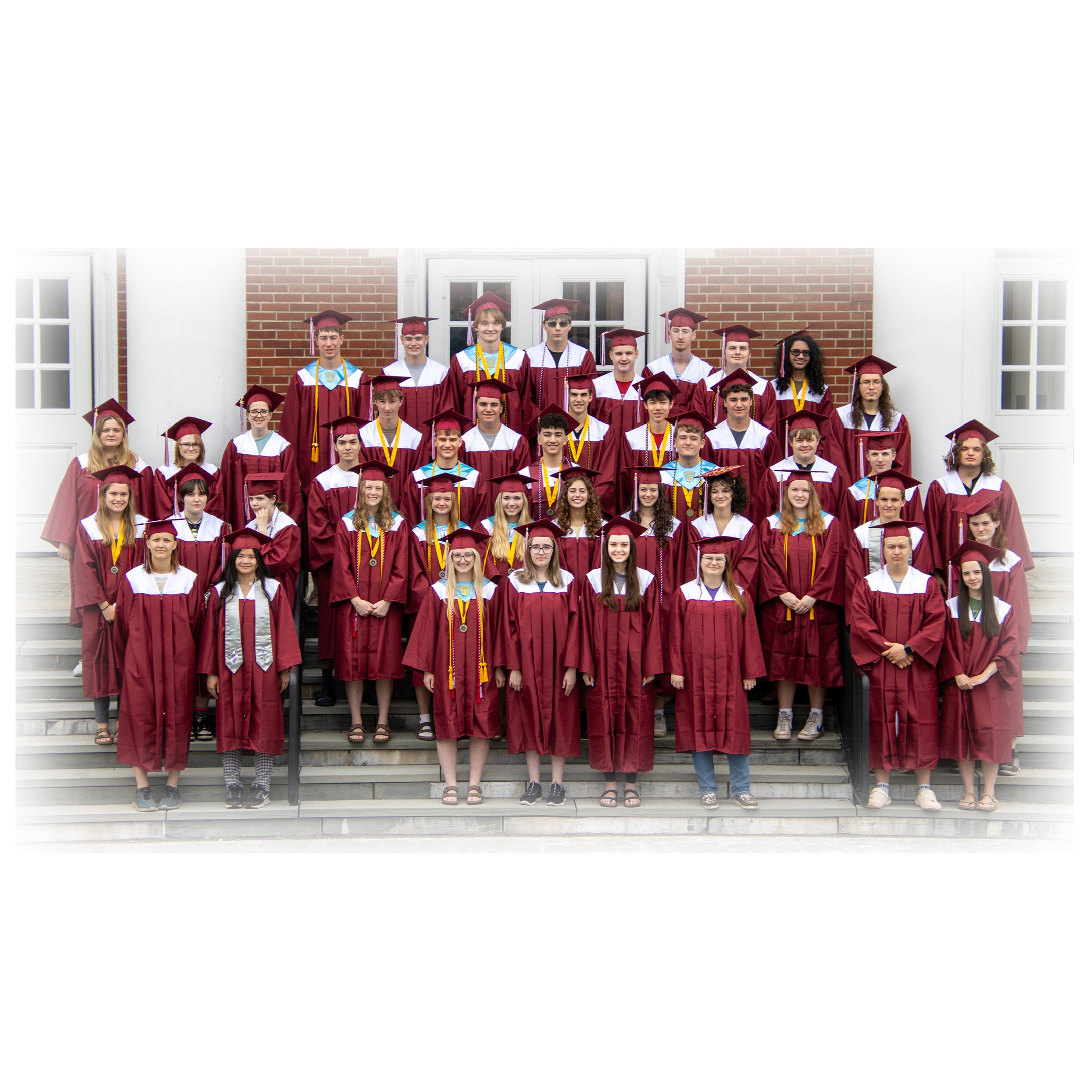 seniors in caps and gowns on steps of school