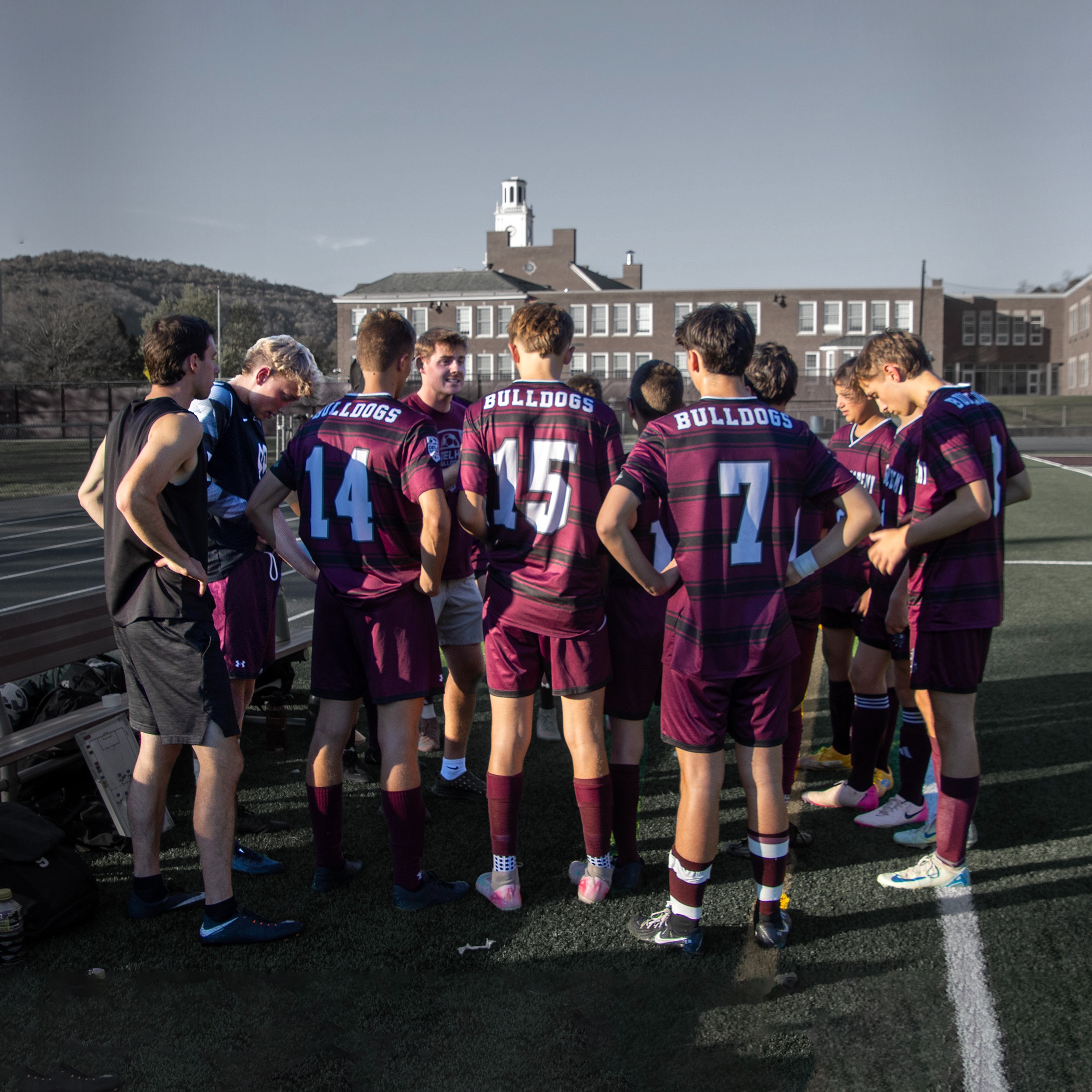 boys soccer coach talking to team in huddle