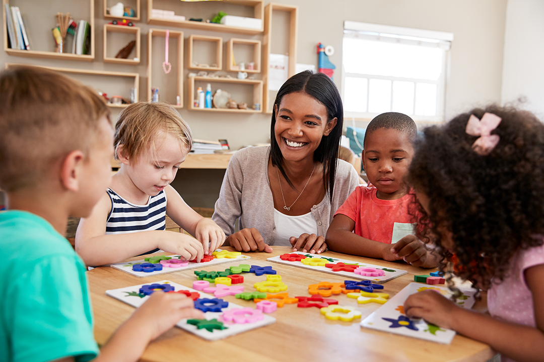 Students working on an activity on a table in class with a teacher