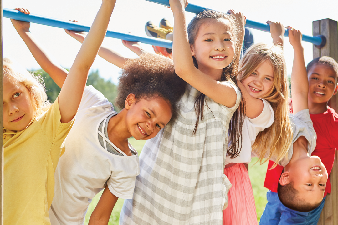 Kids hanging around a playground, specifically monkey bars