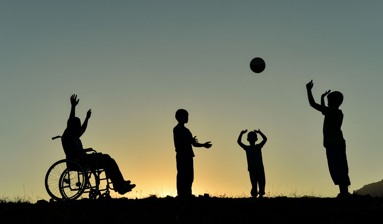 Four children playing. One child is in a wheelchair