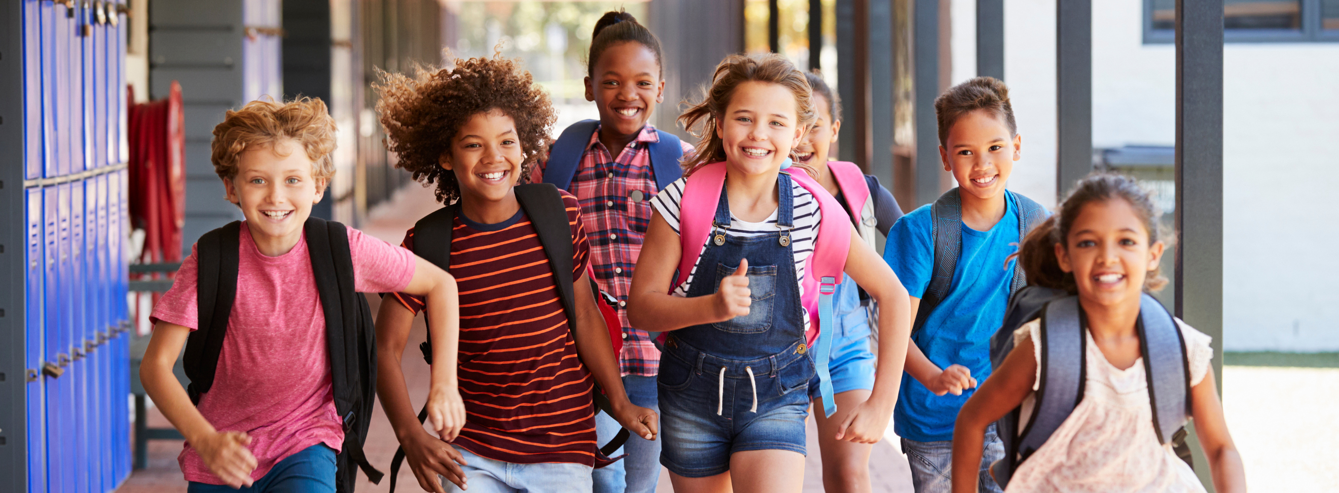 Elementary school students running in outdoor hallway