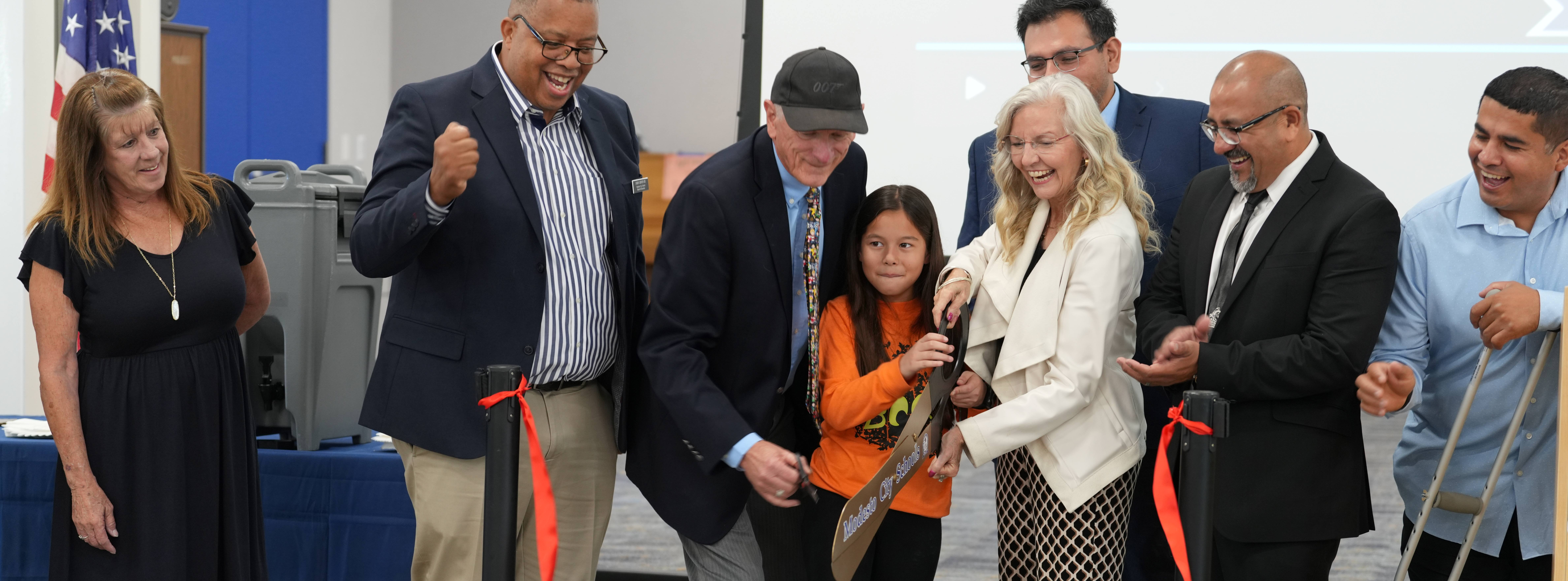 MCS Board Trustees, and John Muir Elementary School leaders, staff, and students cut the ceremonial ribbon to mark the opening of the new multipurpose cafeteria building.