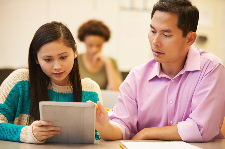 An adult male assisting a female student