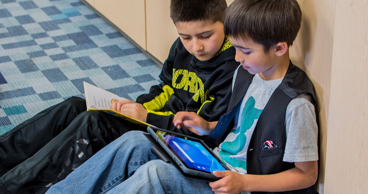 Two kids working with an i[ad