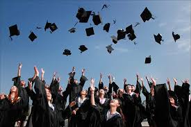 Graduates in gowns toss their black caps in the air