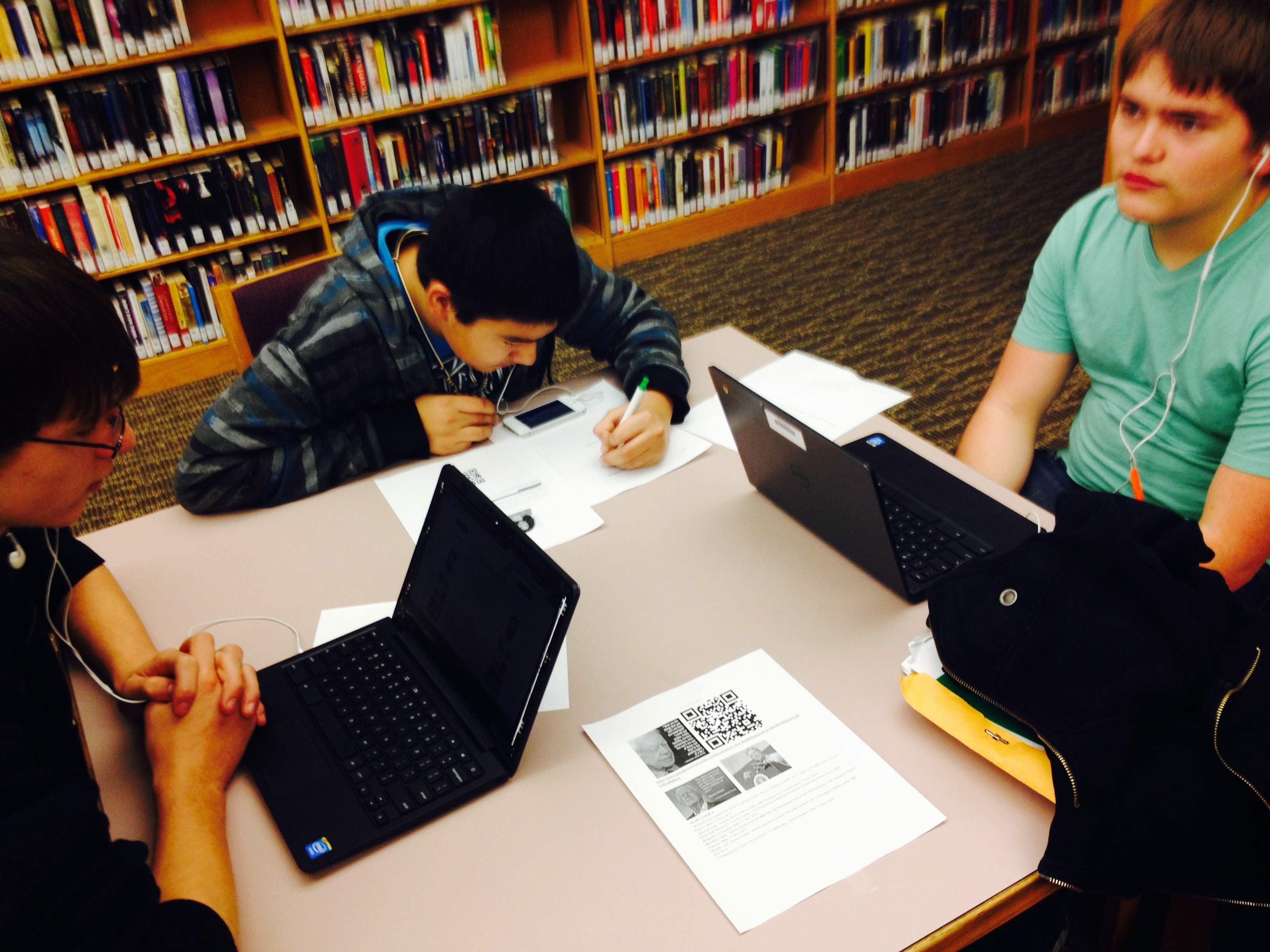 Students working on papers and on Chromebooks in the library