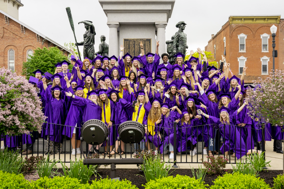 Angola Grads in purple caps and gowns pose at the mound