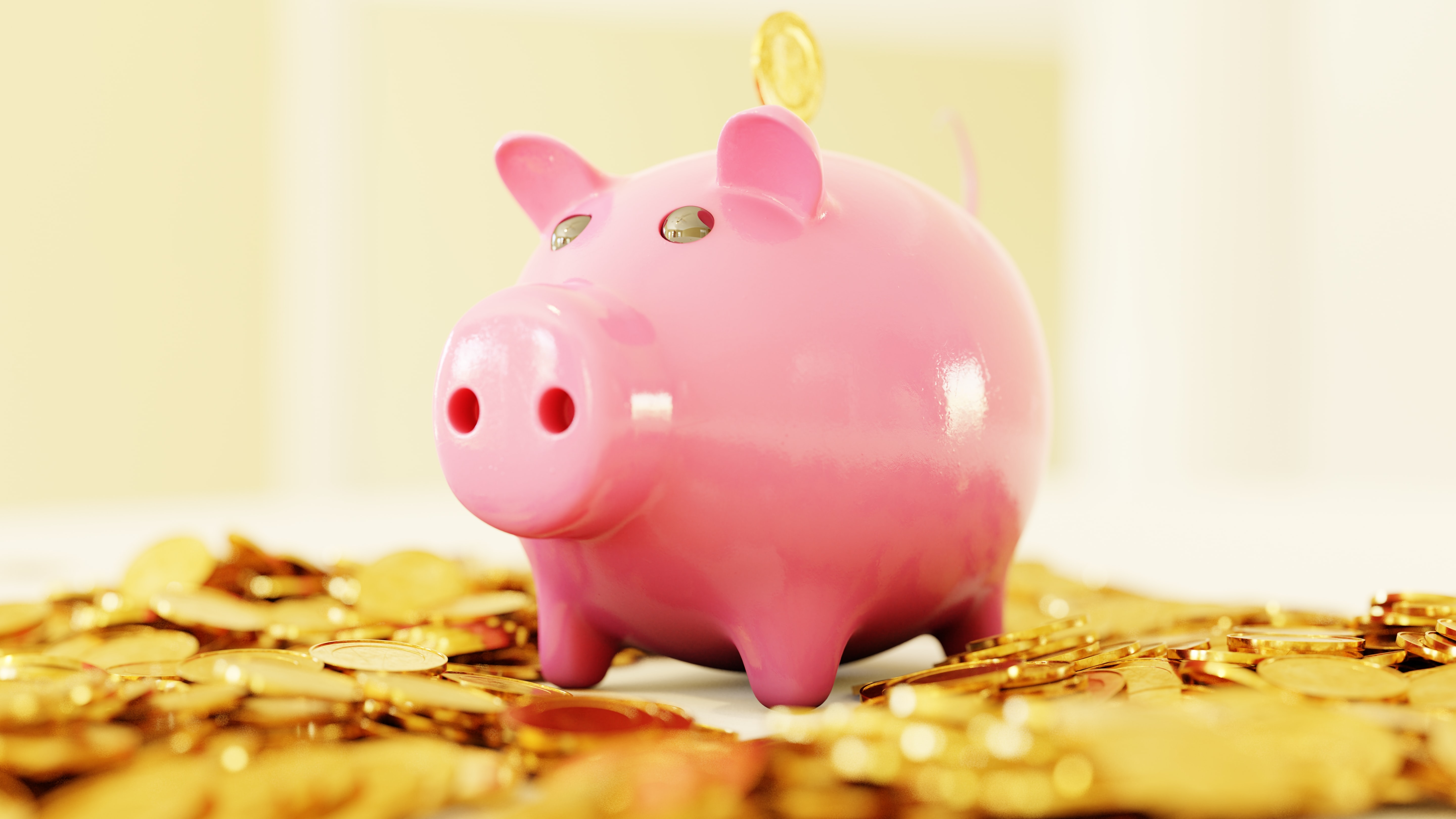 Pink piggy bank sits atop a pile of gold coins