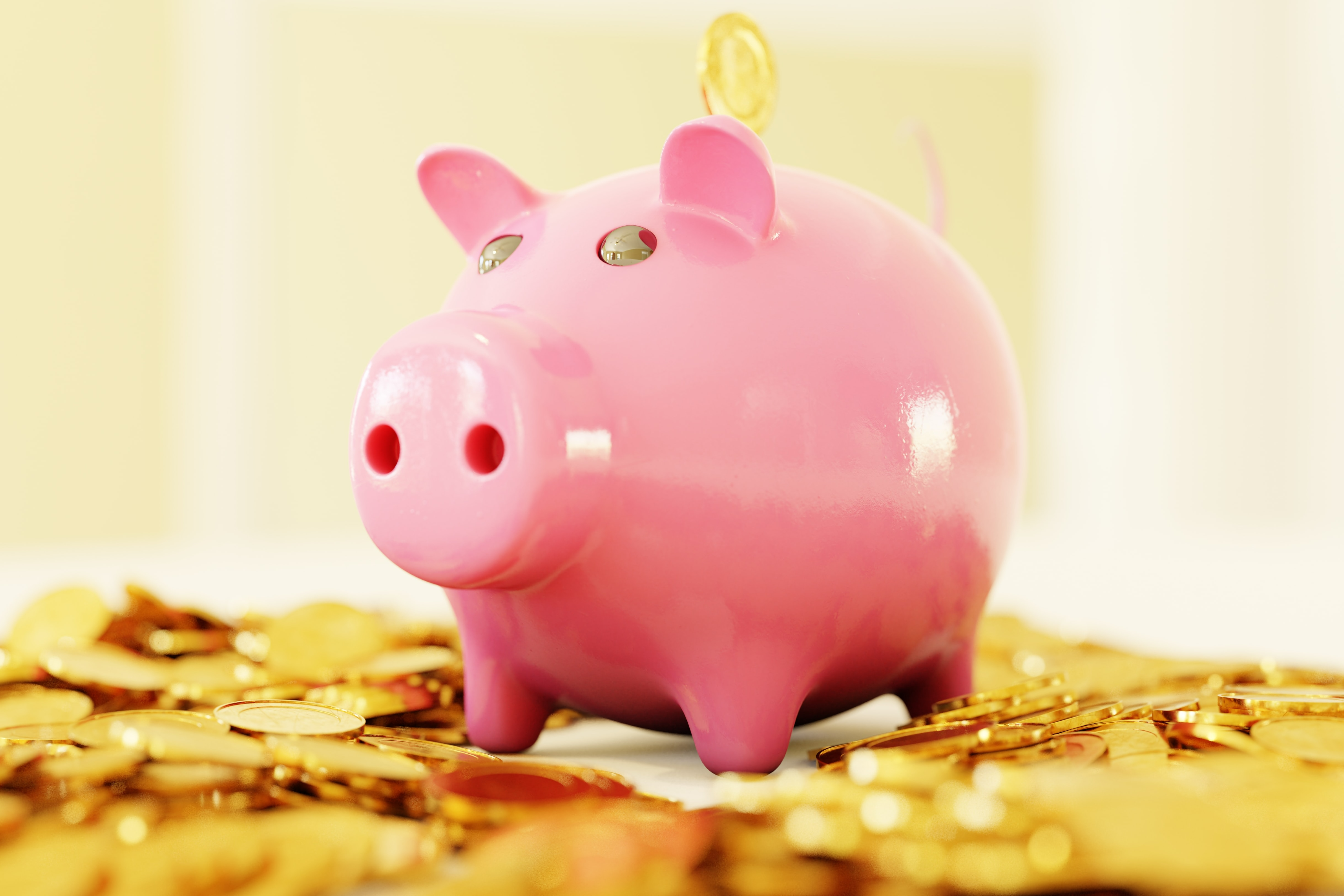 Pink piggy bank sits atop a pile of gold coins