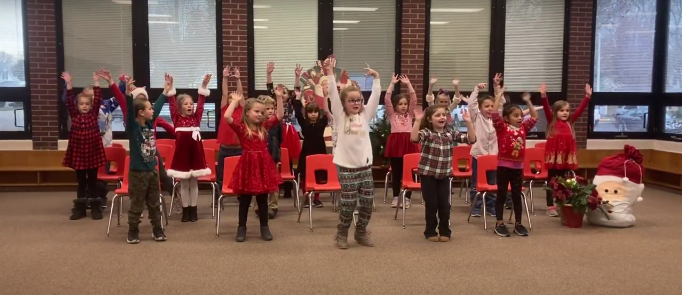 Students in music class, standing up with hands in the air