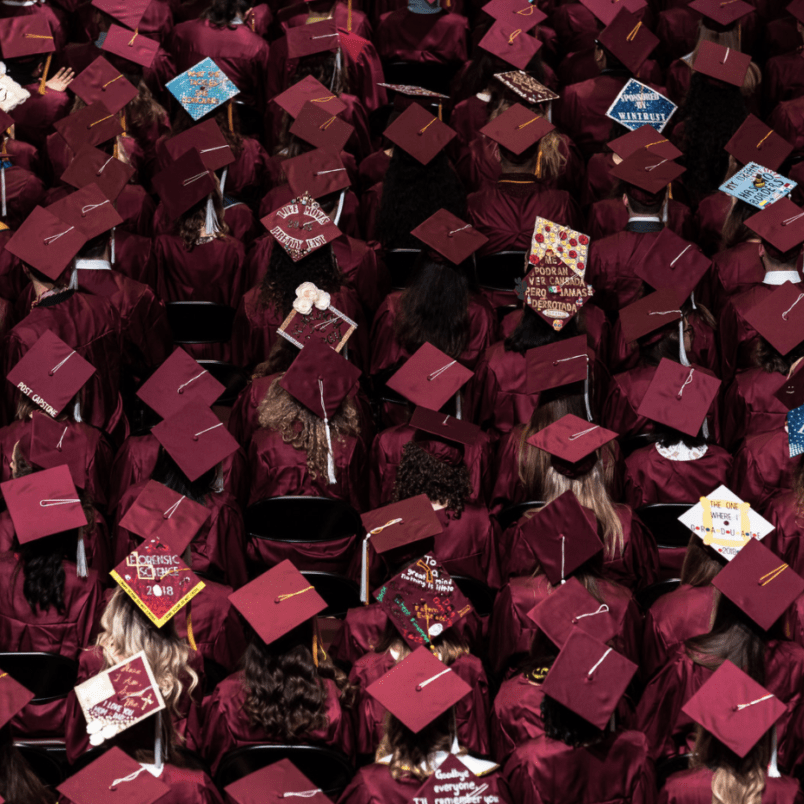 A large group of individuals wearing red graduation caps and gowns, likely at a ceremony.