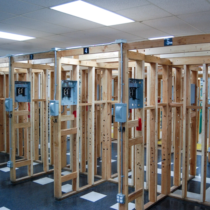 Interior of a building with several wooden structures, each with electrical outlets. The floor is gray and white checkered.