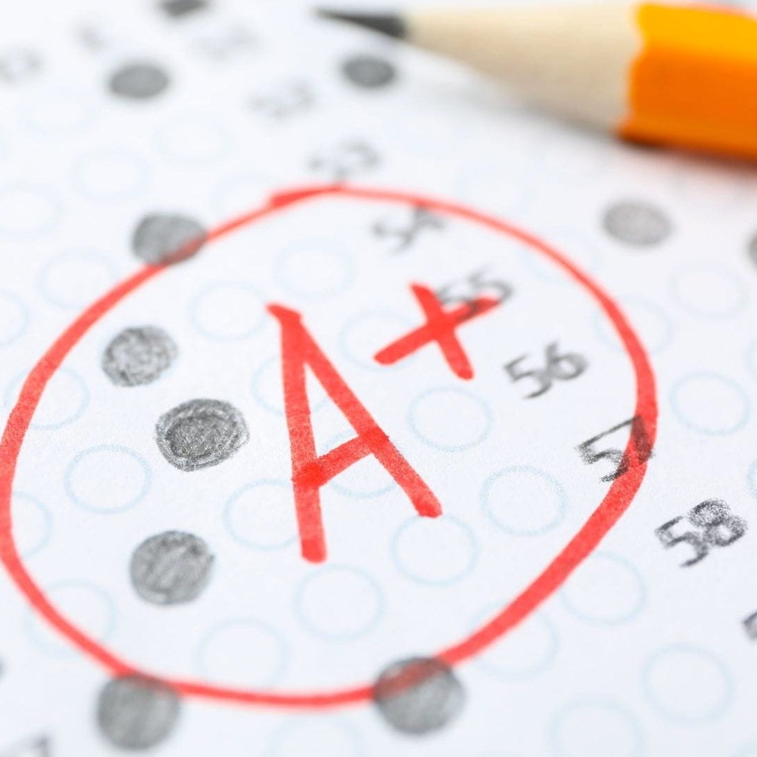 A test paper with a circled A+ grade. A pencil rests on the paper next to the grade.