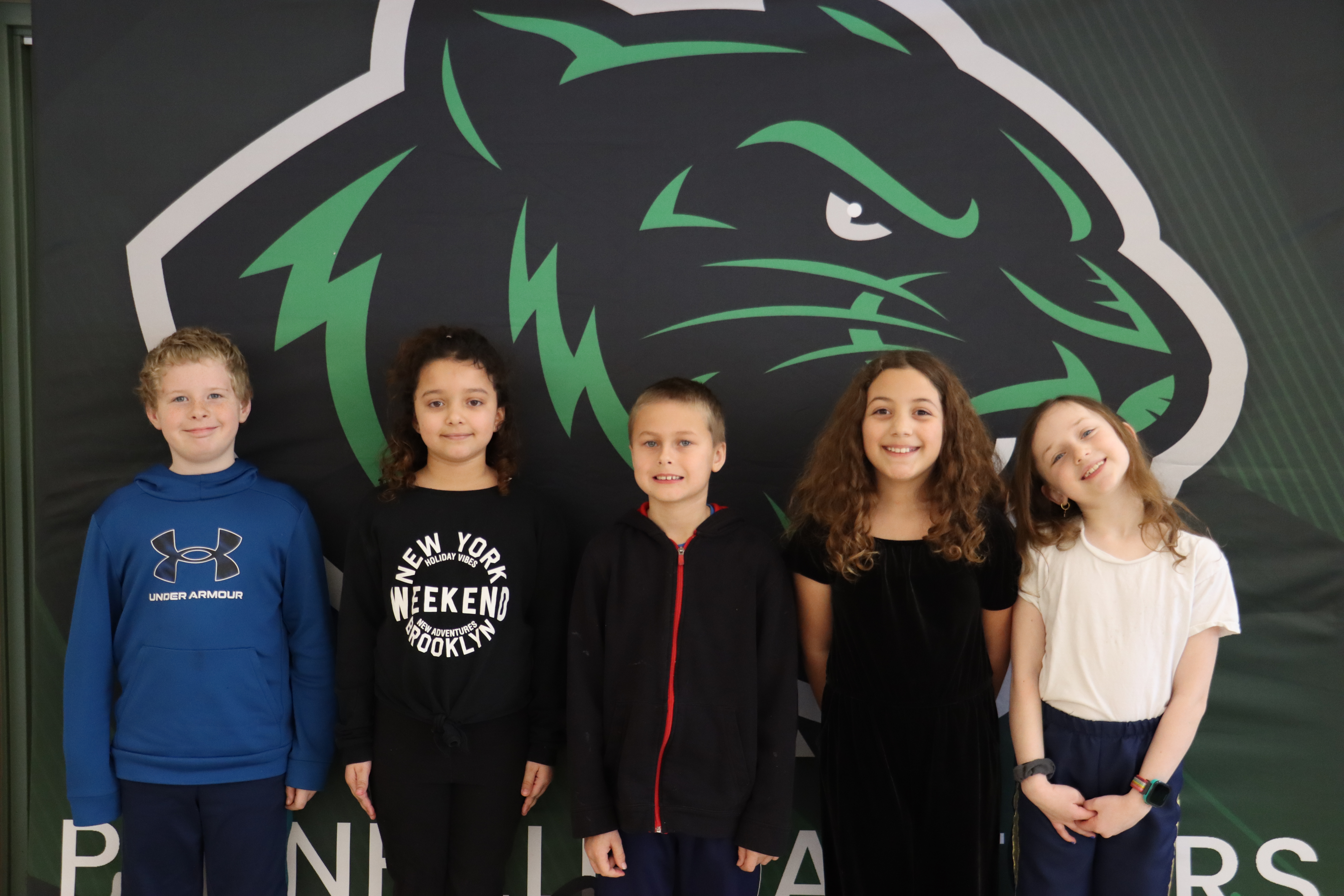 Students smiling for photo, standing in front of panther backdrop