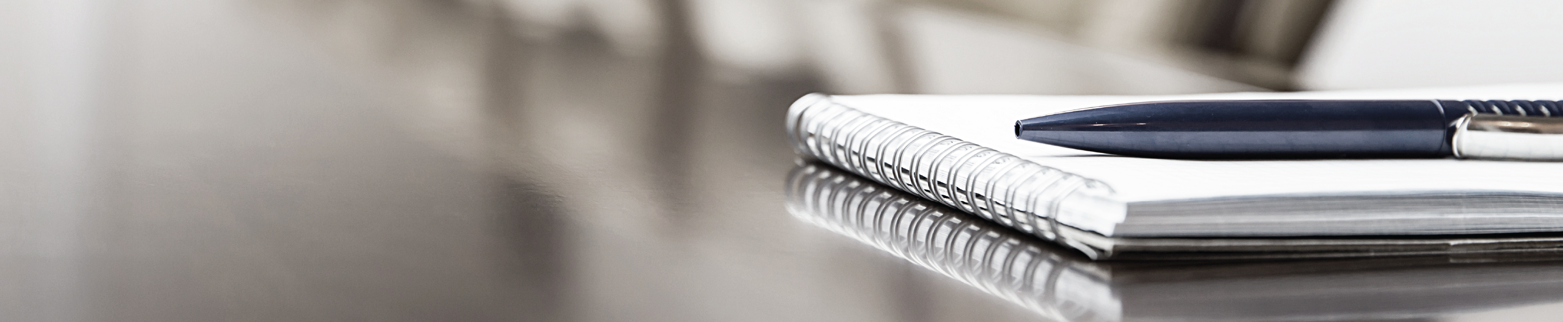 Notebook and pen lying on boardroom table.